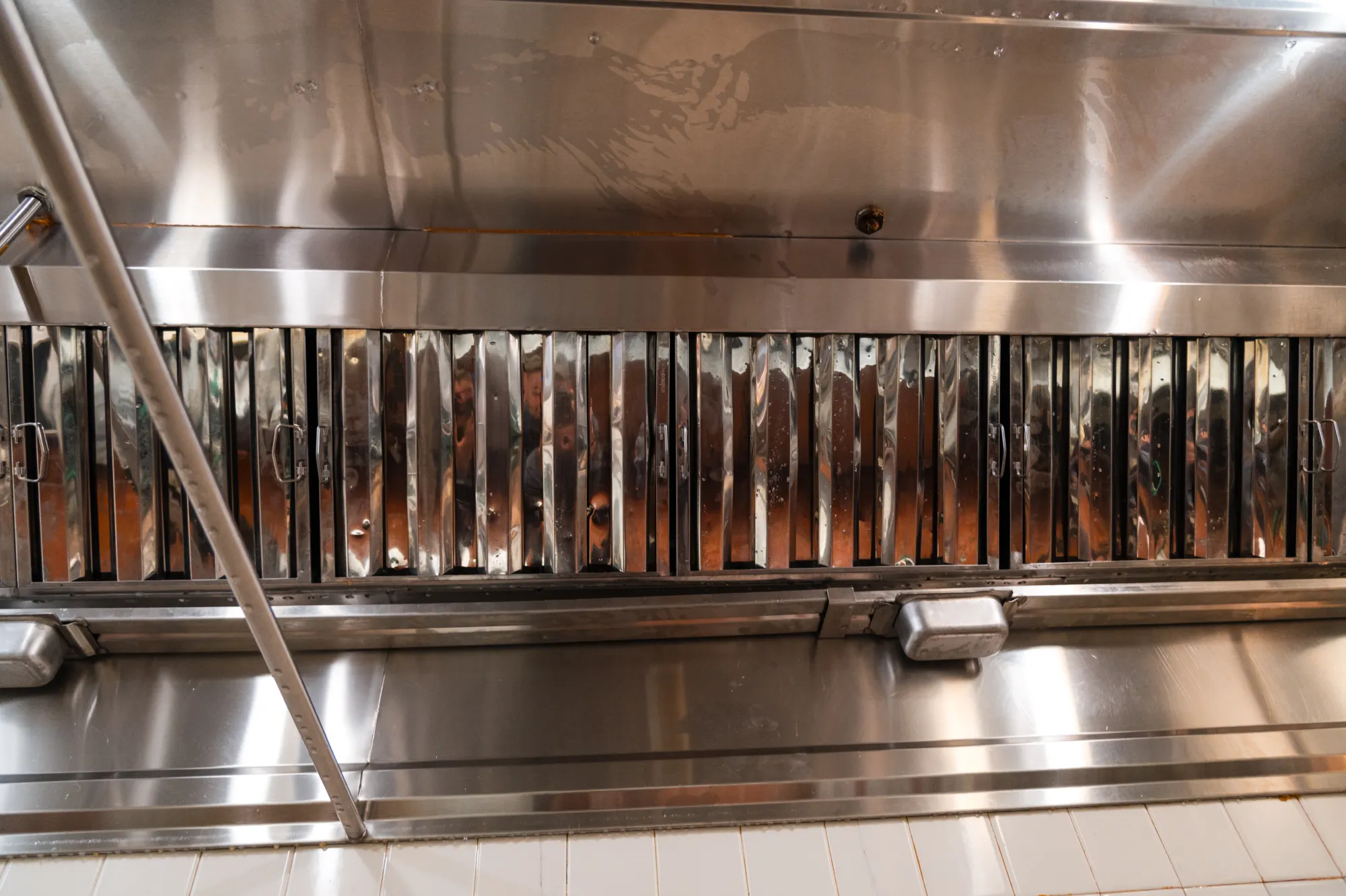 Close-up of a stainless steel commercial kitchen exhaust hood with metal vent filters.