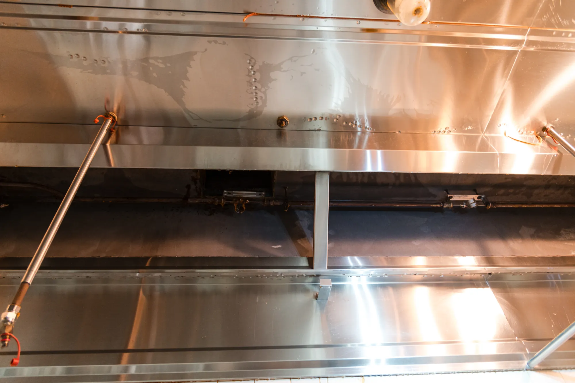 A close-up view of a stainless steel commercial kitchen exhaust hood and vent system.