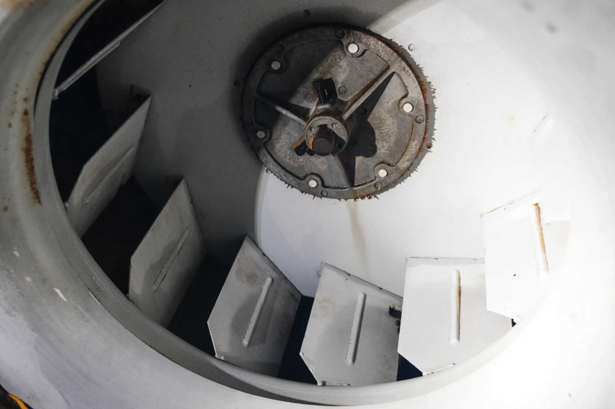 Close-up of the inside of a metal machine with angled blades and a central circular hub.