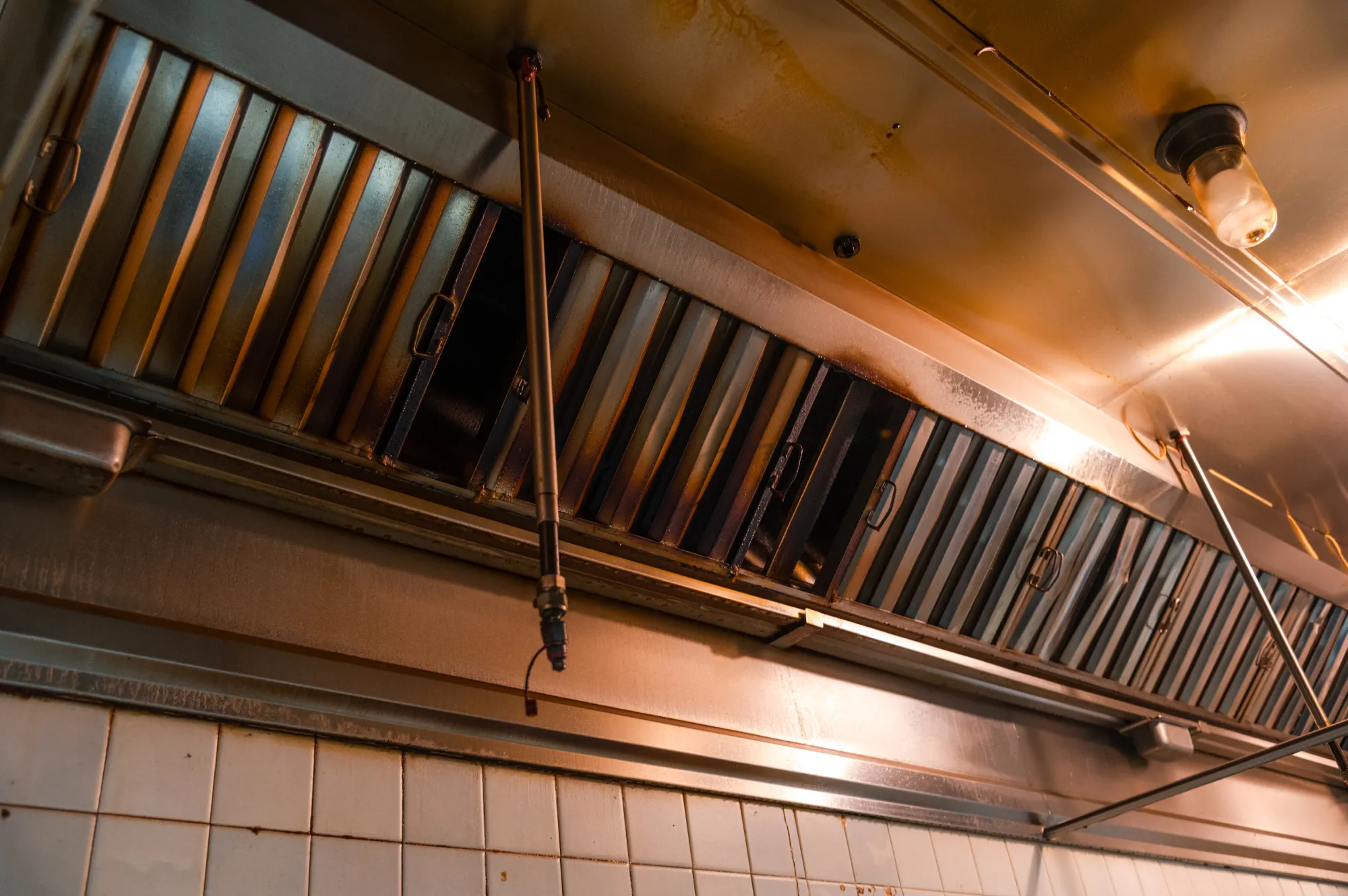 Commercial kitchen metal exhaust hood and vent system with overhead lighting.