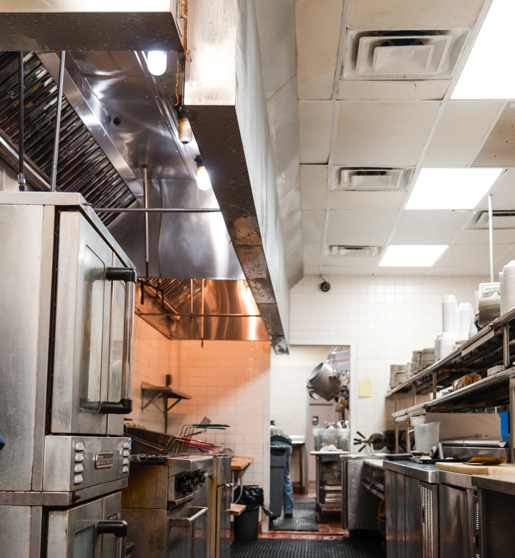 A clean, empty commercial kitchen with stainless steel appliances and bright overhead lights.