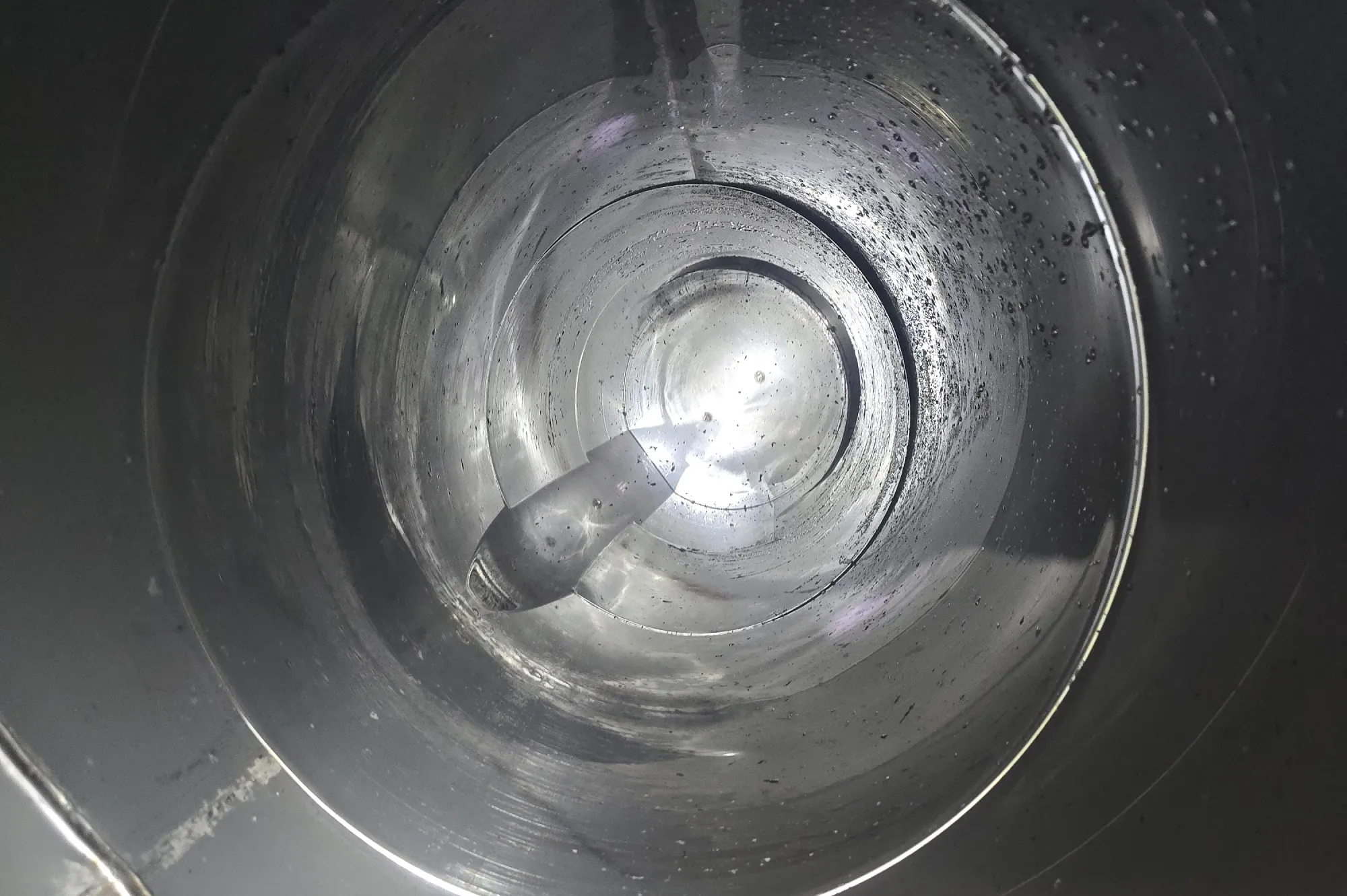 Inside view of a shiny metal cylinder with light reflecting and illuminating its smooth, circular walls.
