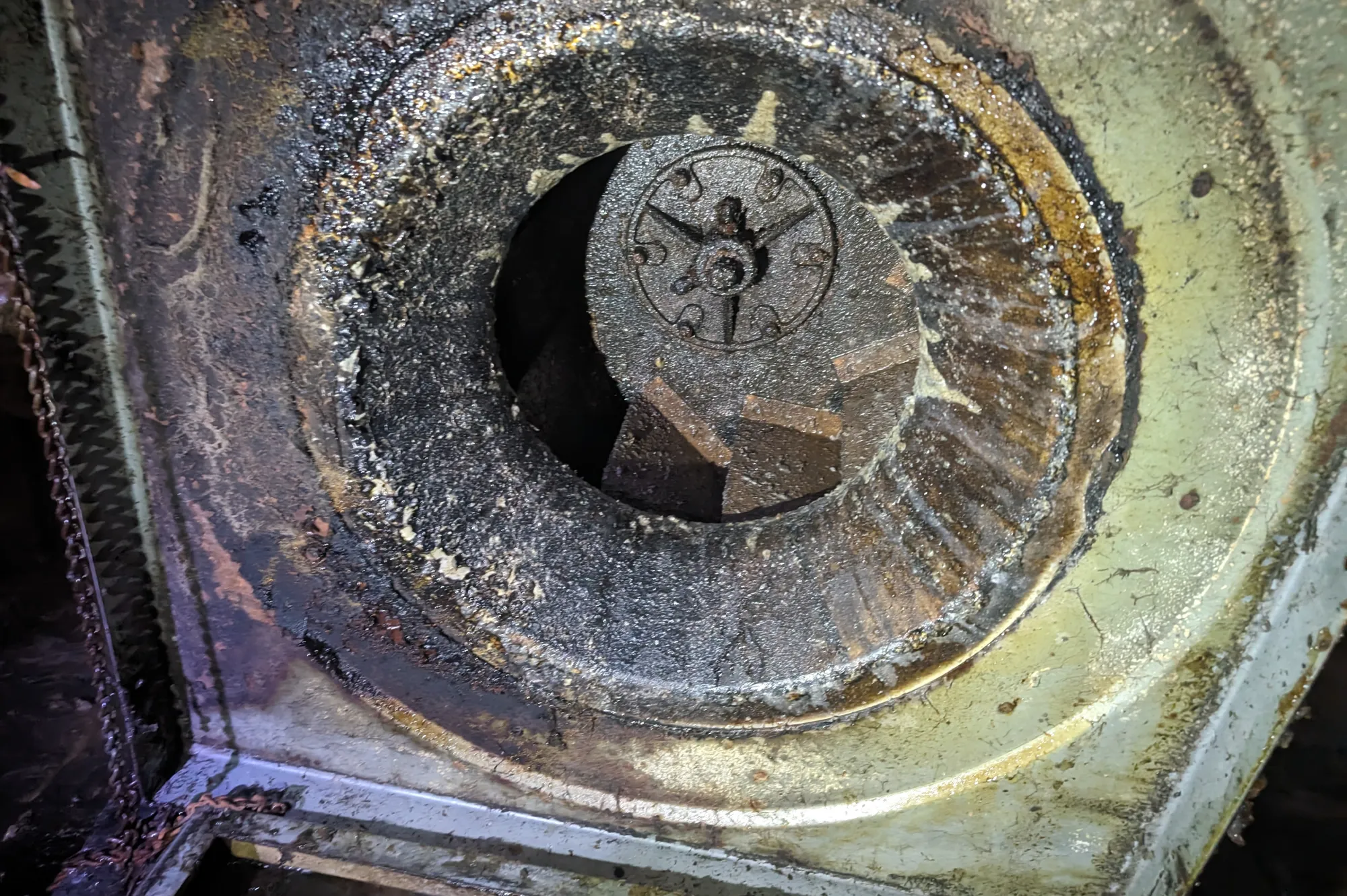 Close-up of a dirty, greasy industrial fan or blower with visible buildup on the blades and metal housing.